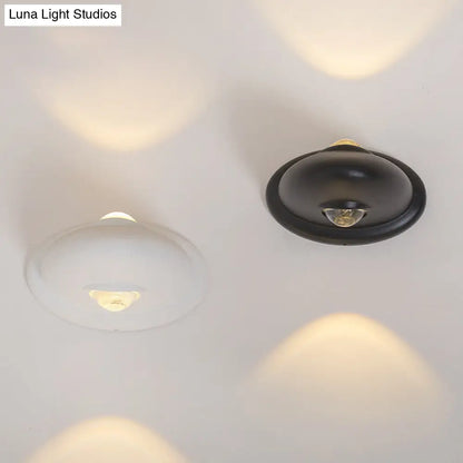 Aplique de pared LED DecorBites™ para dormitorio con pantalla triangular contemporánea de aluminio y acabado en blanco y negro con iluminación blanca cálida.