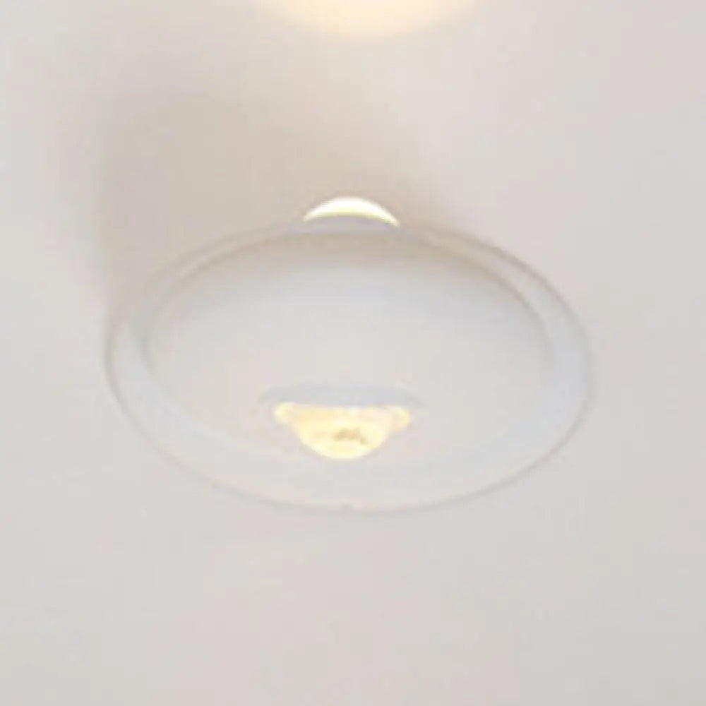 Aplique de pared LED DecorBites™ para dormitorio con pantalla triangular contemporánea de aluminio y acabado en blanco y negro con iluminación blanca cálida.