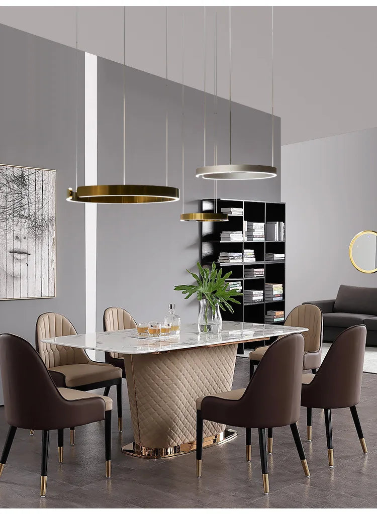 Modern led chandelier light with round rings design above a marble dining table with beige diamond metal base and gold accents
