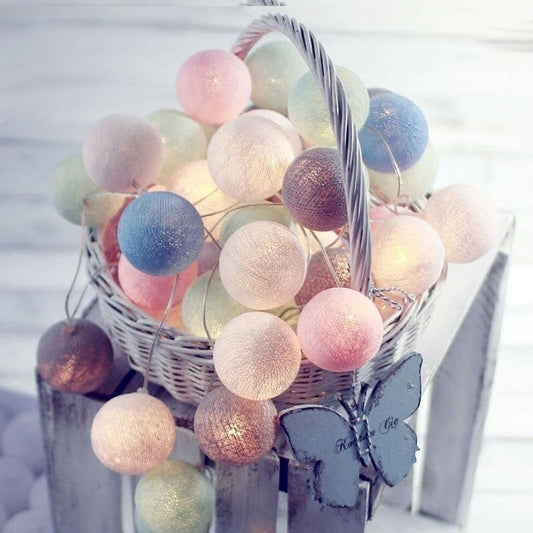 Pastel-colored cotton ball string lights with butterfly accents in a white wicker basket.