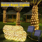 Warm white led solar strip rope lights coiled on grass with two black solar panels for outdoor garden decor