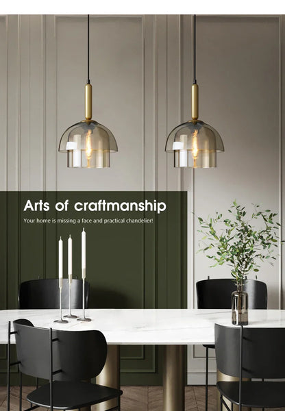 Two modern led vintage art champagne chandeliers with smoked glass domes and brass accents hanging over dining table