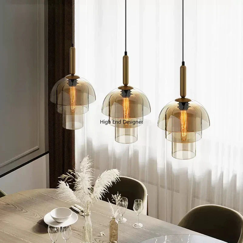 Three amber glass shade led vintage art champagne pendant lamps with brass fixtures hanging above dining table