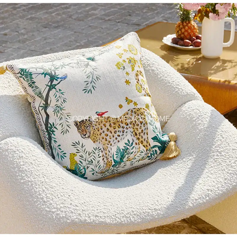 White decorative cushion cover with detailed leopard jungle scene in green yellow teal hues and gold tassels decorbites leopard decorative