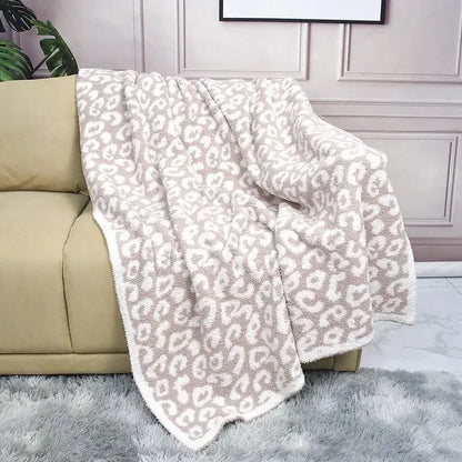 A cozy beige and white leopard print sherpa throw blanket made of flannel velvet draped over a tan sofa decorbites cozy flannel
