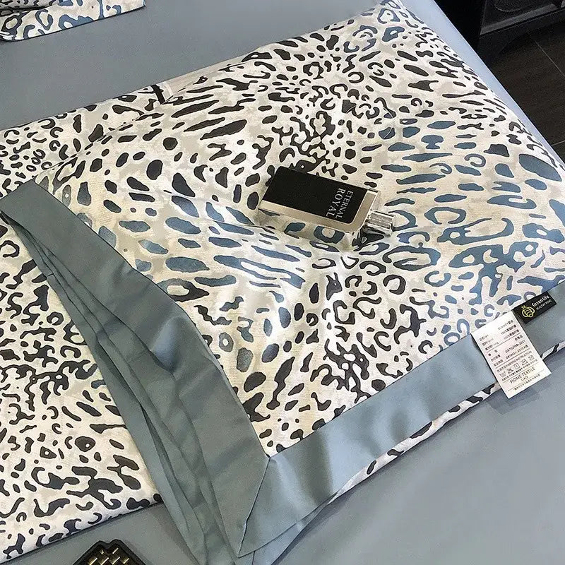 A luxurious cream satin leopard print pillow sham with bold black and blue pattern and gray satin piping for decorbites leopard print summer decor