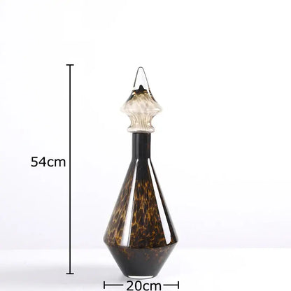 A 54cm tall leopard print glass decanter with dark amber and black tortoiseshell pattern and clear faceted stopper