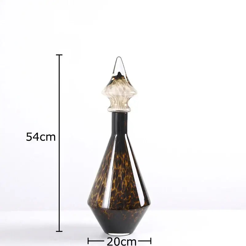 A 54cm tall leopard print glass decanter with dark amber and black tortoiseshell pattern and clear faceted stopper