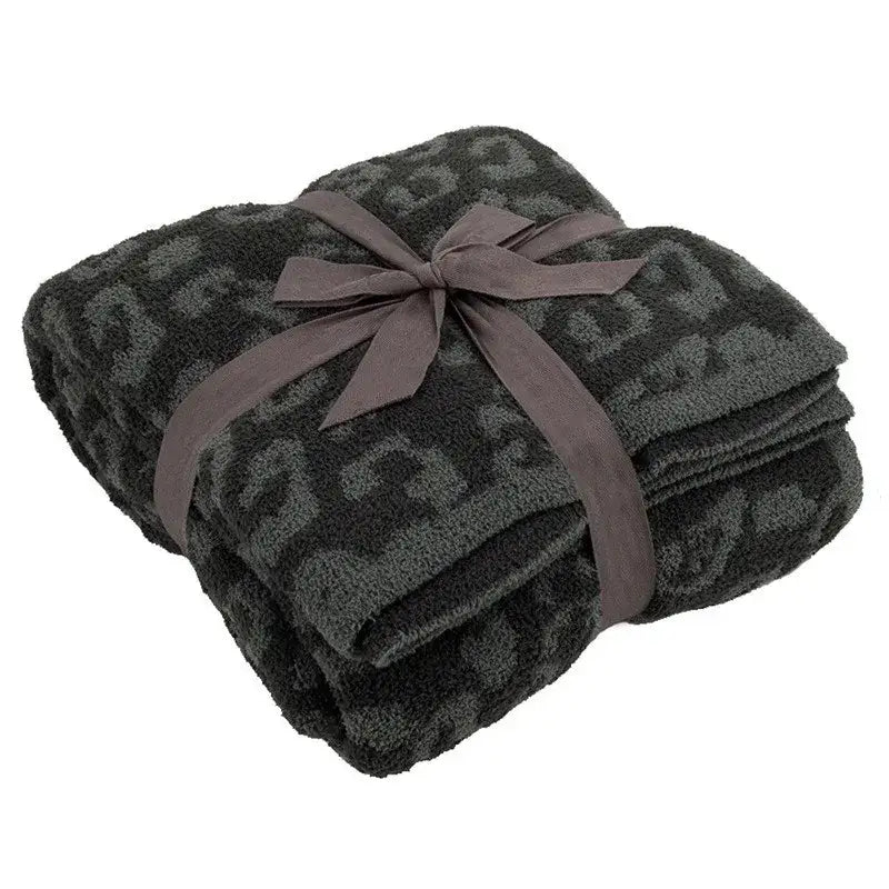 A plush dark gray leopard print fleece blanket tied with a matching satin ribbon by decorbites for sofa or bedroom