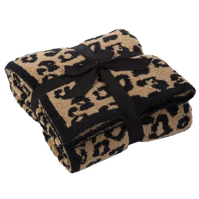 A plush tan and black leopard print fleece blanket tied with a black satin ribbon decorbites leopard print throw