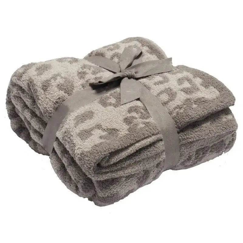 A taupe fleece blanket with subtle leopard print tied with satin ribbon from decorbites leopard print collection