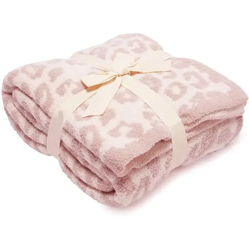 A soft pink leopard print fleece blanket tied with a cream satin ribbon decorbites leopard print throw