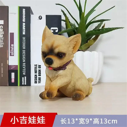 A tan resin chihuahua figurine with a purple collar and black nose sitting in front of books decorbites dog sculpture