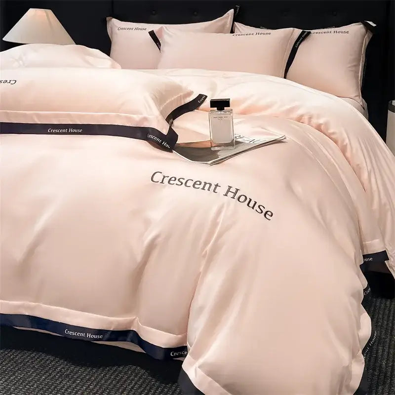 Blush pink satin duvet cover set with black crescent house branding and ribbons from decorbites ice silk bed set