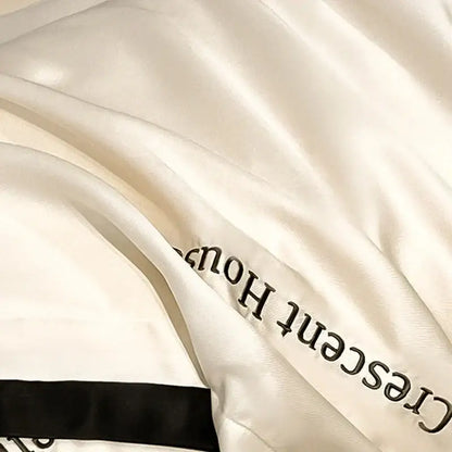 Cream-colored satin decorbites ice silk duvet cover bed set with black embroidered text and ribbon trim for bedroom decor