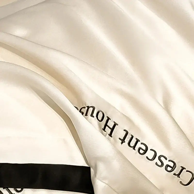 Cream-colored satin decorbites ice silk duvet cover bed set with black embroidered text and ribbon trim for bedroom decor