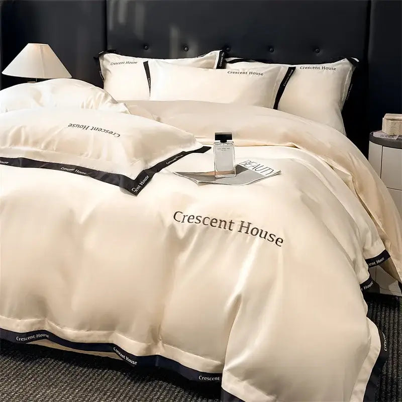 Cream-colored satin duvet cover bed set with black trim and crescent house branding from decorbites ice silk collection