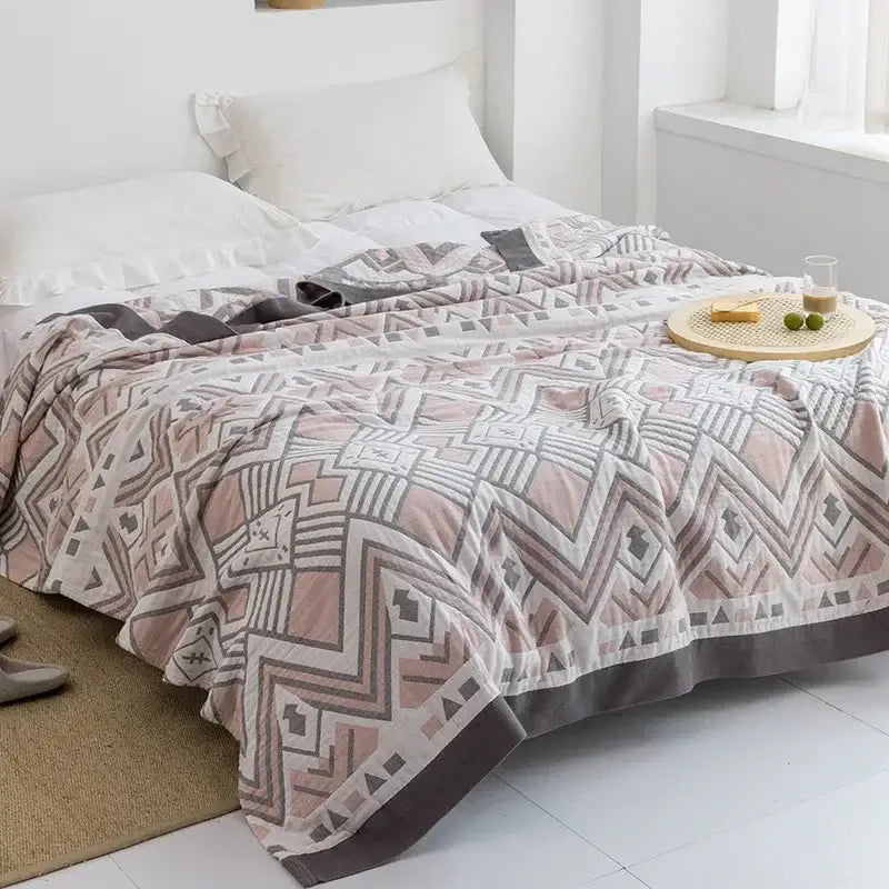 A soft pastel pink and gray geometric-patterned cotton gauze towel throw with subtle sheen for bedroom decorbites cotton gauze