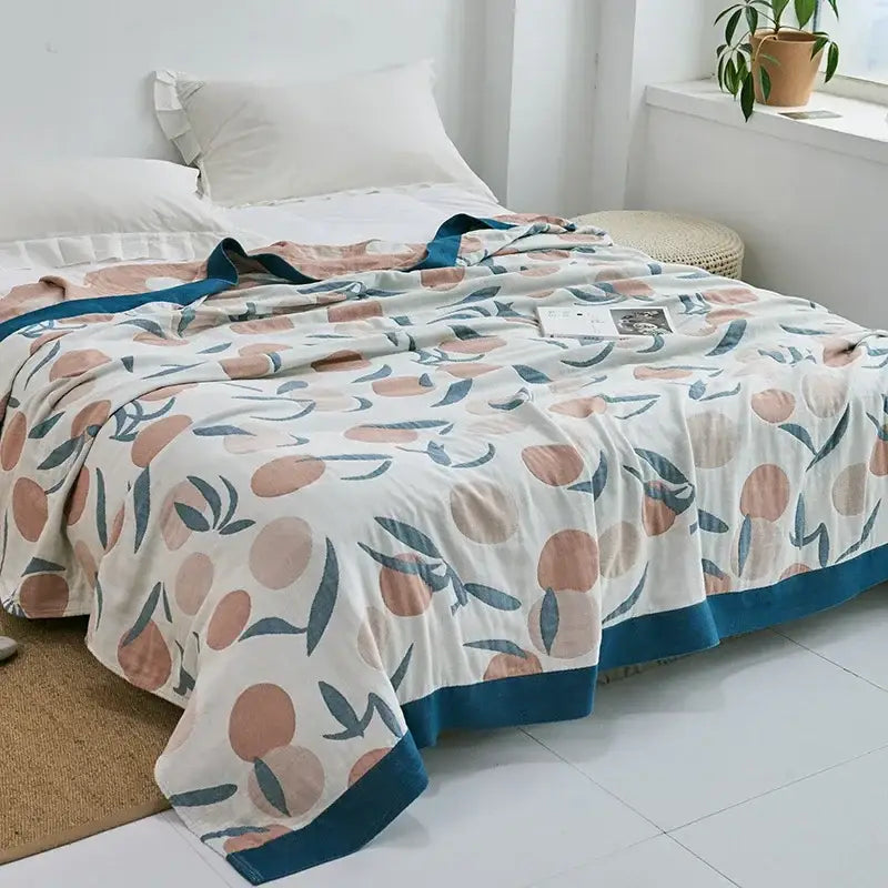 A cream cotton gauze towel throw with playful peach and leaf pattern and teal border for bedroom decorbites cotton gauze