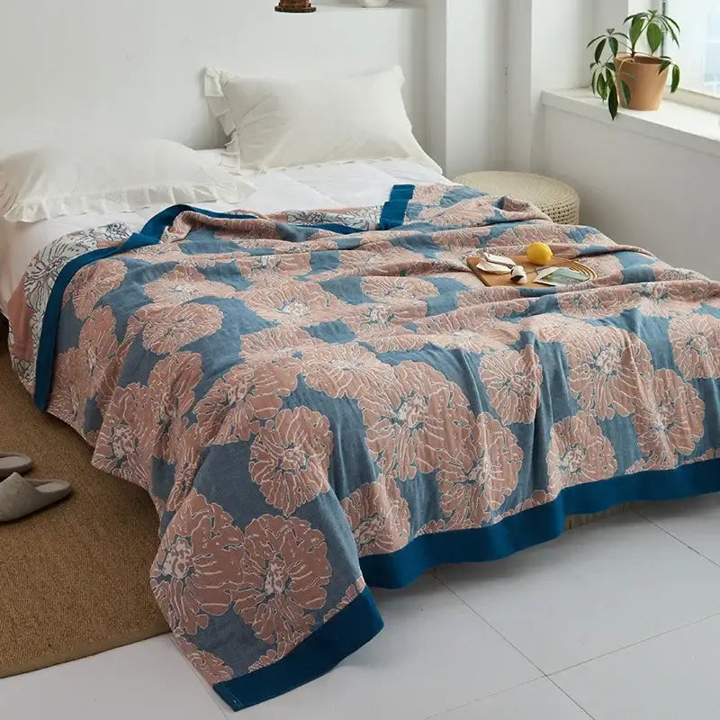 A soft blue and blush pink floral decorbites cotton gauze towel throw with a solid navy border for bedroom decor