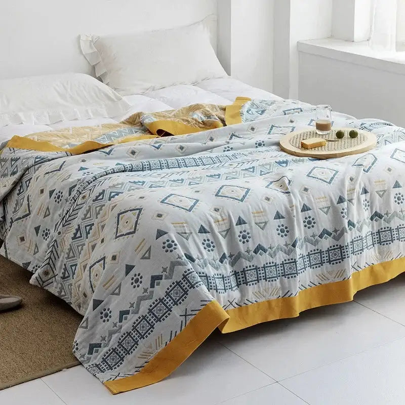 Light gray quilted decorbites cotton gauze towel throw with blue and mustard geometric pattern and bold border trim