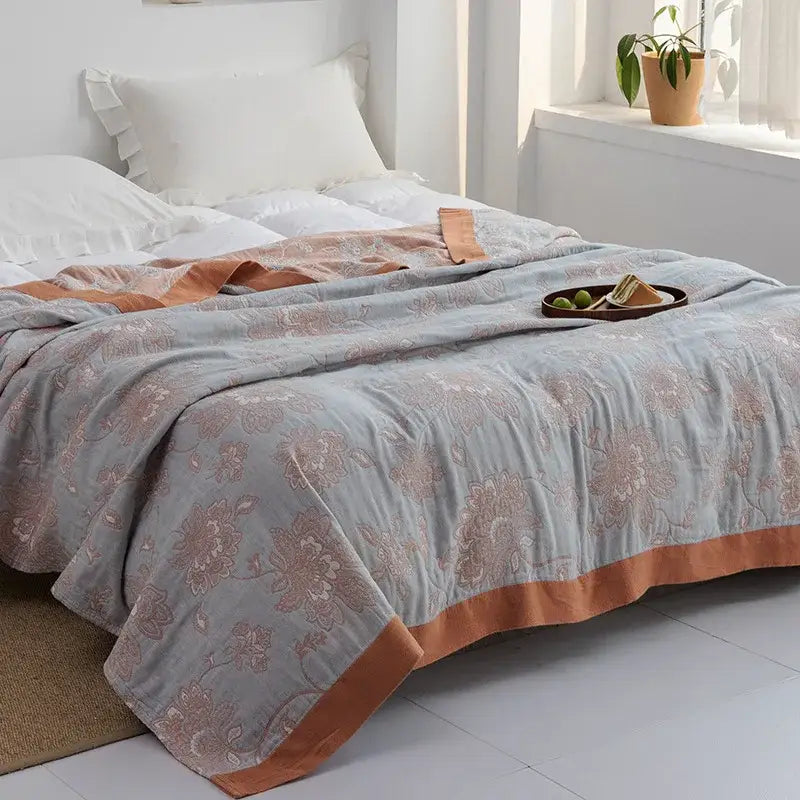 A soft gray cotton gauze towel throw with muted peach floral pattern and rust binding for bedroom decorbites cotton gauze