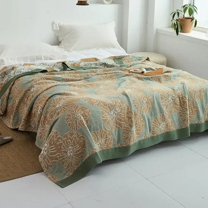 A soft sage green and beige floral patterned decorbites cotton gauze towel throw with subtle textured weave