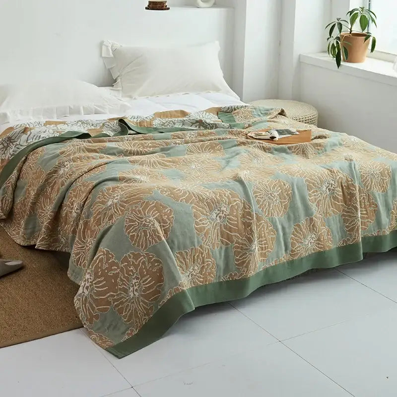 A soft sage green and beige floral patterned decorbites cotton gauze towel throw with subtle textured weave