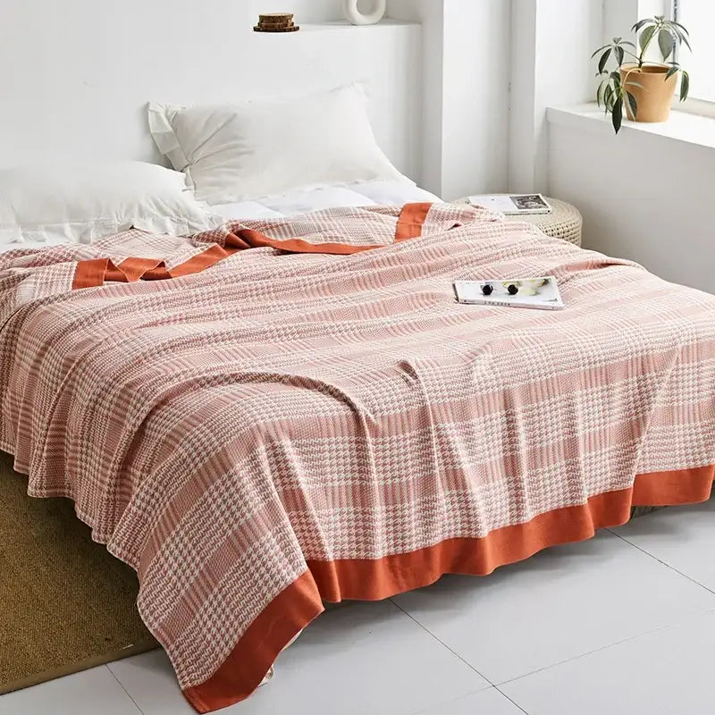 A soft peach and cream plaid decorbites cotton gauze towel throw with a solid orange border for bedroom decor