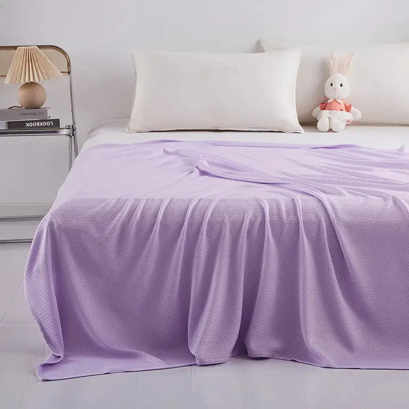 A soft lavender bamboo fiber summer quilt with textured woven pattern draped over the bed decorbites bamboo fiber