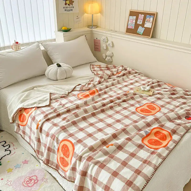 A cream and rust plaid cozy milk velvet blanket with cartoon orange slices featuring soft fleece texture for decorbites cozy milk
