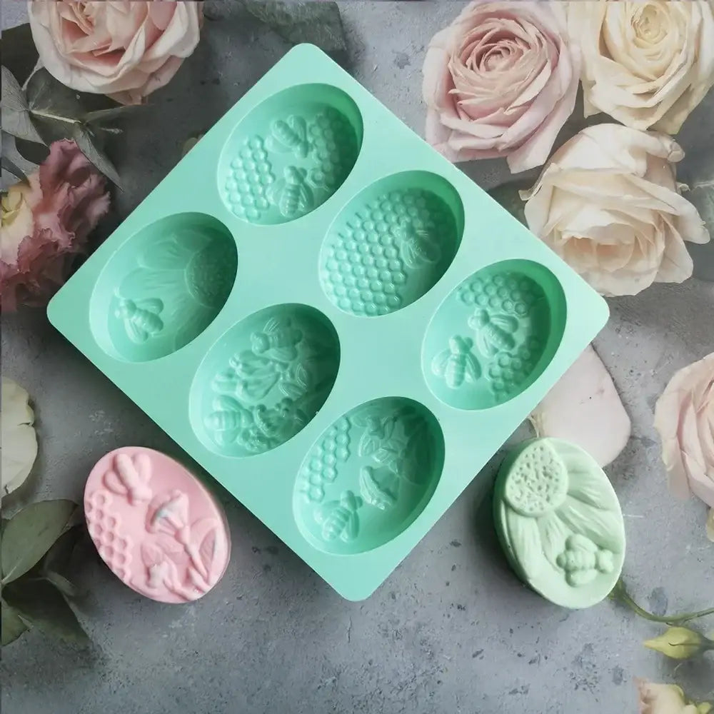 Light blue bee silicone soap mold with six oval cavities featuring bee and floral designs for kitchen use