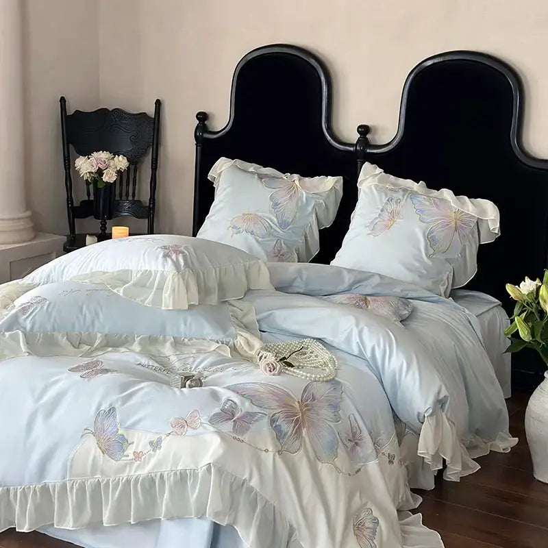 Light blue satin bedding set with delicate butterfly embroidery, soft ruffled edges, and decorbites french lace accents