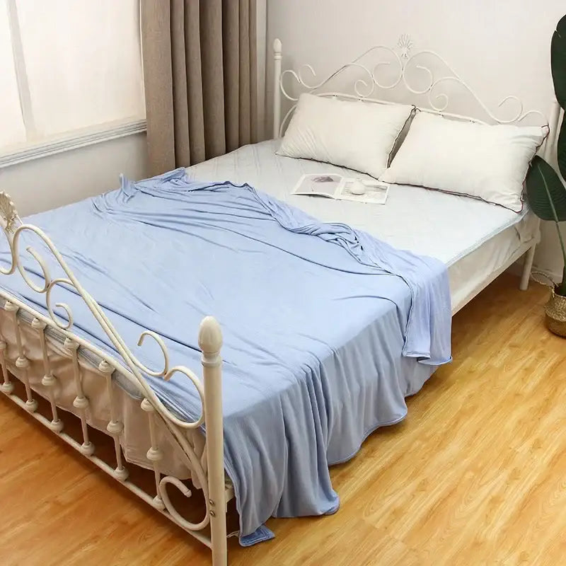 Light blue soft textured bed sheet draped over white wrought iron bed frame decorbites cool feel summer blanket