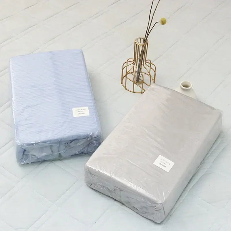 Two decorbites cool feel summer bed sheets in light blue with stripes and muted gray wrapped in clear plastic packaging
