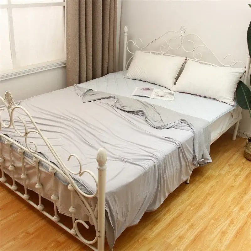 White wrought iron bed frame with ornate scrollwork paired with light blue decorbites cool feel summer blanket