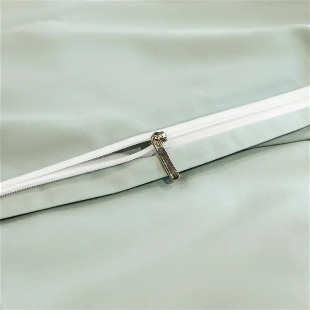 Silver zipper with metallic pull tab on light green fabric of light blue embroidered egyptian cotton bedding set