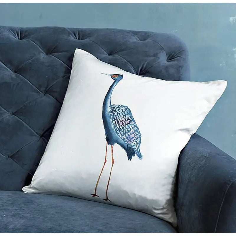 White paradise silk throw pillow cover featuring detailed blue crane embroidery with iridescent feathers and orange legs