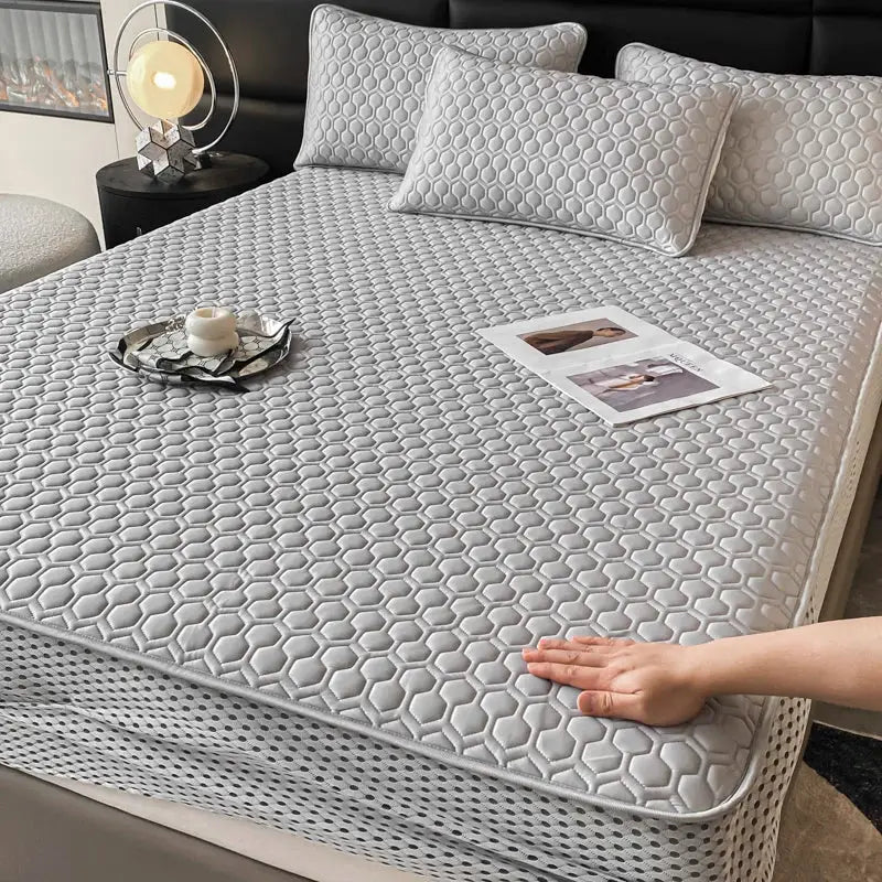 Light blue hexagonal ice silk cooling bed mat set with gray quilted mattress pad featuring stitched edges