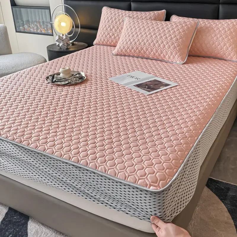 Pink quilted bed mat set with honeycomb texture and gray trim designed as a cooling mattress pad