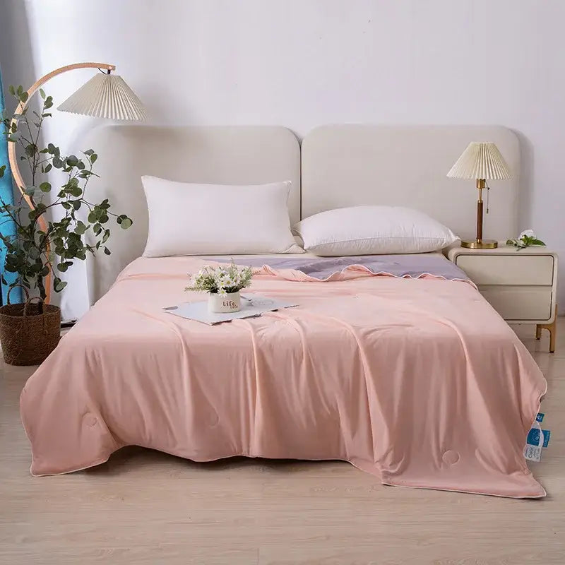 Soft pink satin-like bedspread with subtle sheen draped elegantly as an air conditioning quilt for summer bedroom use