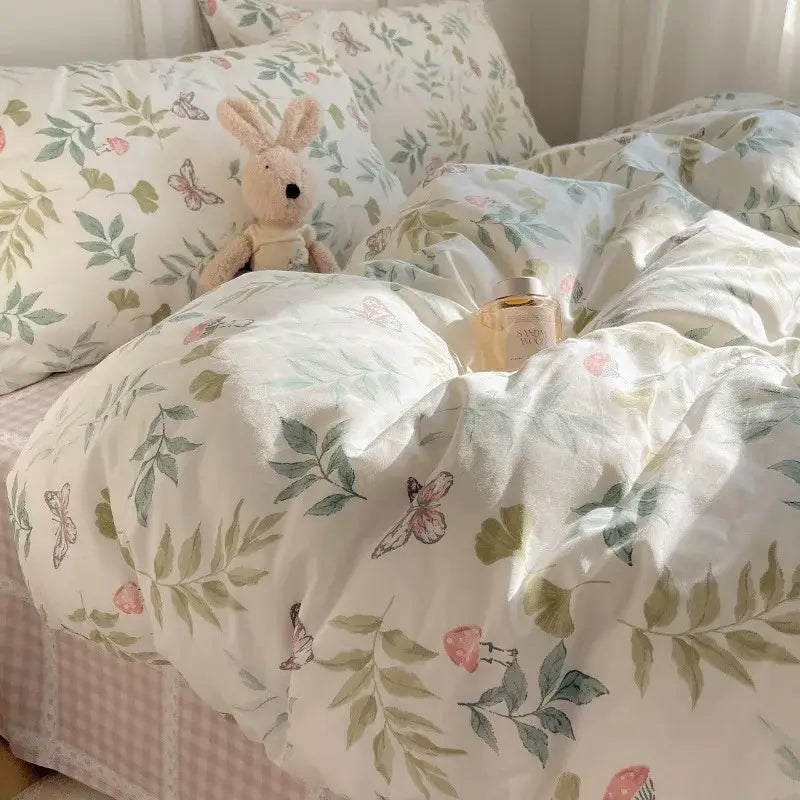 A soft cream-colored duvet cover with green leaves and pink butterflies in a light blue puppy cartoon pattern bedding set