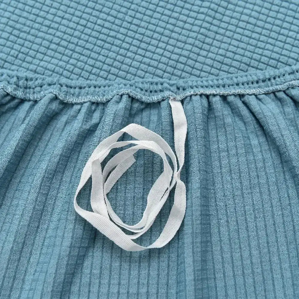A white elastic ribbon on teal fabric of a light blue decorbites 3d quilted thicken sofa cover for living room couch