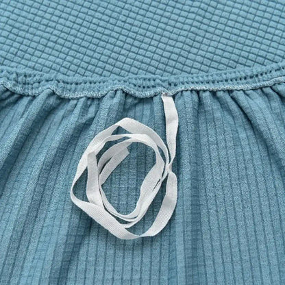 A white elastic ribbon on teal fabric of a light blue decorbites 3d quilted thicken sofa cover for living room couch