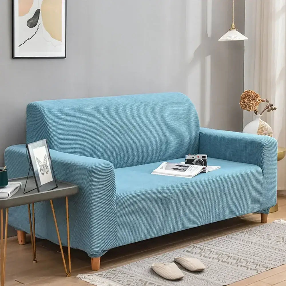 A light blue quilted thicken sofa cover from decorbites 3d quilted fits snugly over a modern loveseat