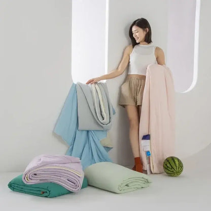 A woman stands beside neatly folded light blue and white decorbites cooling fabric summer blankets for bedroom comfort