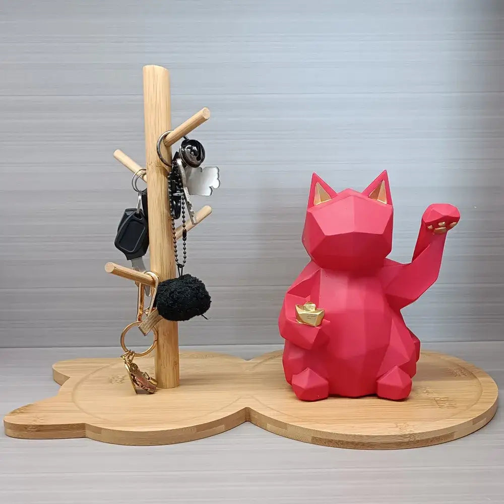 Light brown wooden key rack holder with a vibrant red geometrically designed lucky cat figurine and gold accents