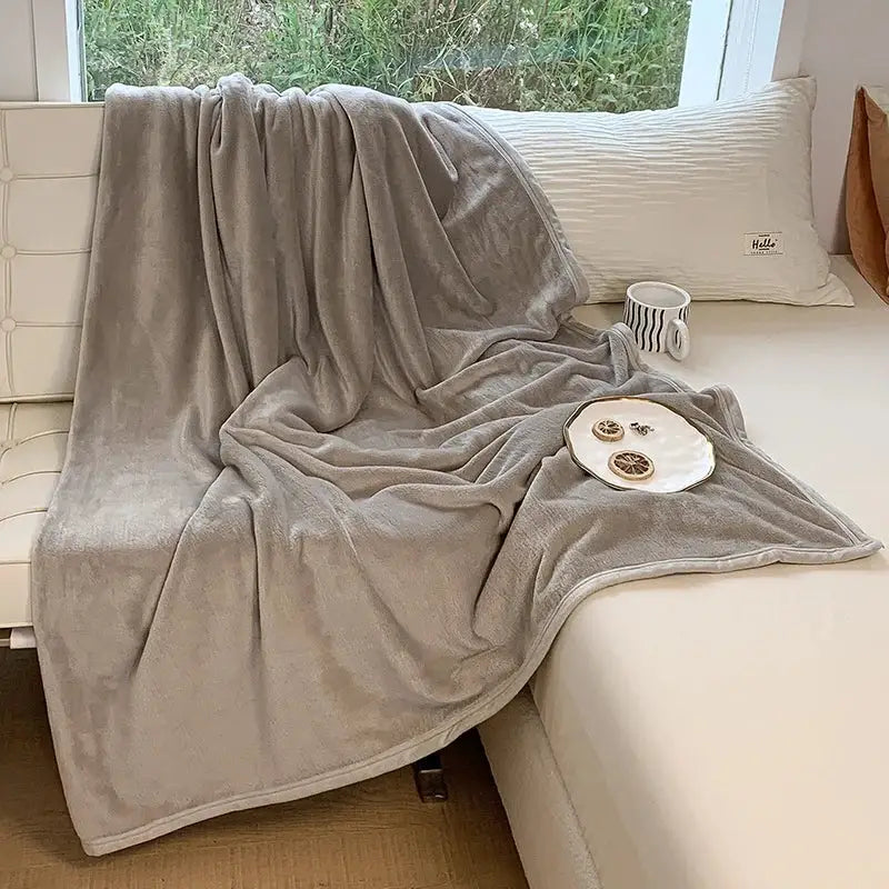A soft, plush light gray coral velvet summer blanket draped over a couch for cozy bedroom decorbites coral velvet use