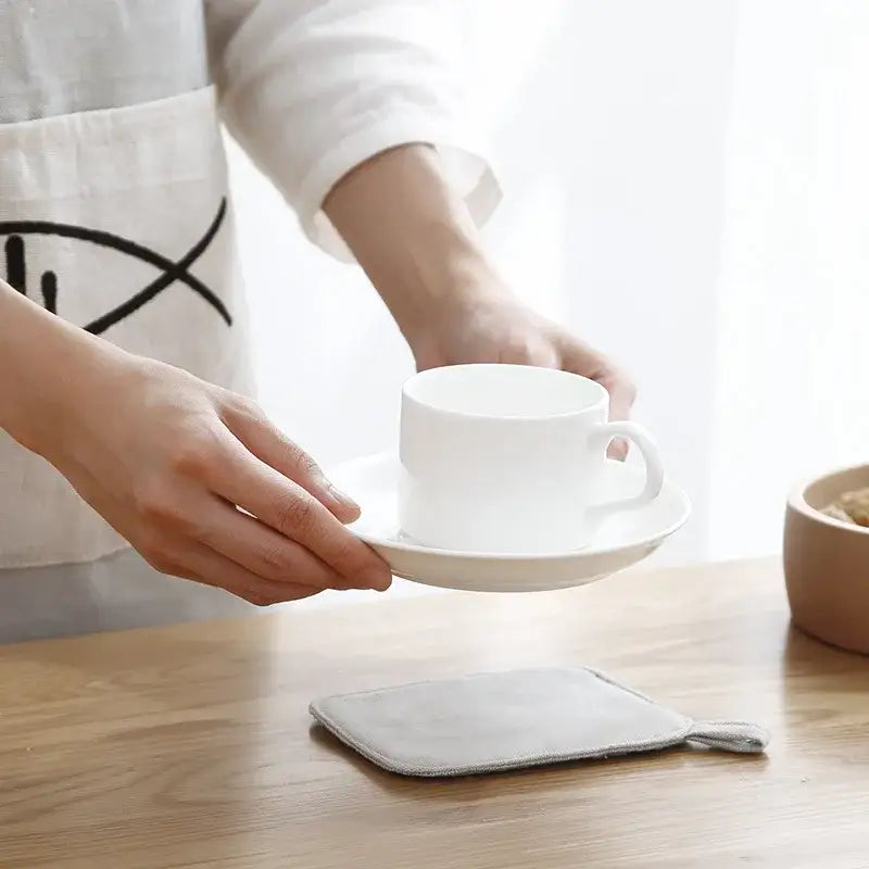 White ceramic coffee cup on light gray cotton linen coaster set with handle held in kitchen decorbites cotton linen coaster