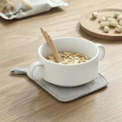 Light gray cotton linen coaster set with handle displayed under a white ceramic bowl with rolled oats and wooden spoon, decorbites cotton linen coaster